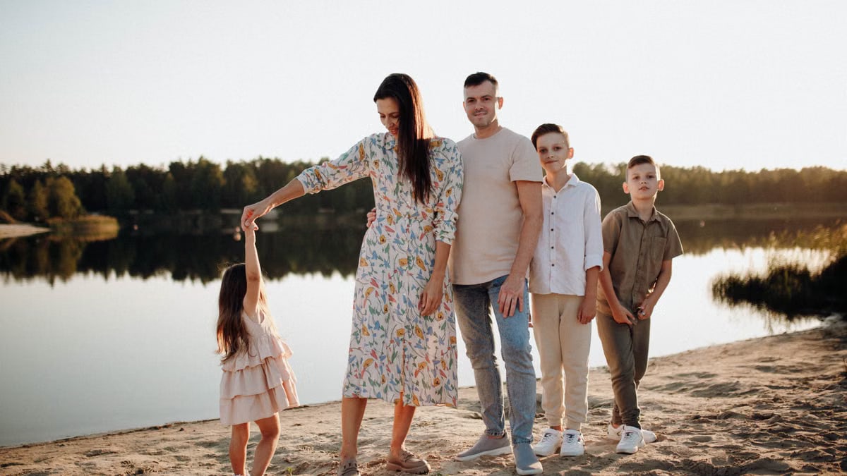 A family of five enjoys a serene lakeside vacation at sunset, capturing precious moments together.